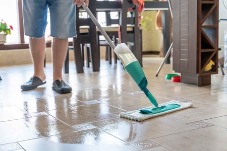 Mopping tile floors to clean them.