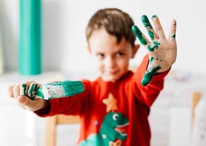 Child with paint on hands and clothes.