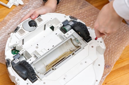 hands-disassembling-a-robot-vacuum-cleaner-for-mai-web