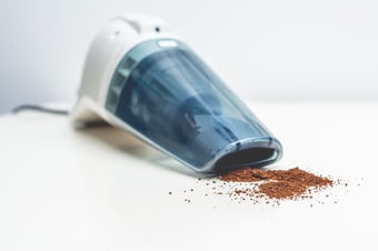 small-vacuum-cleaning-brown-dust-on-white-surface-web